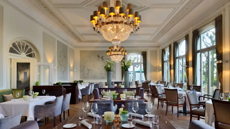 Salle avec tables, chaises et lustres élégants.
