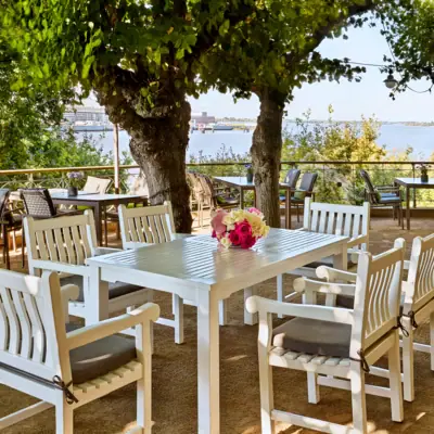 Table de Liebermann Ensemble de tables blanches sous les arbres, sur la terrasse du tilleul.