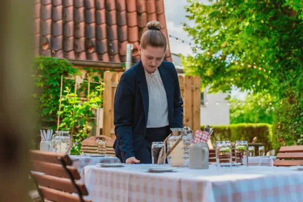 Eine Mitarbeiterin deckt den Tisch im Außenbereich der Weinwirtschaft Kleines Jacob.