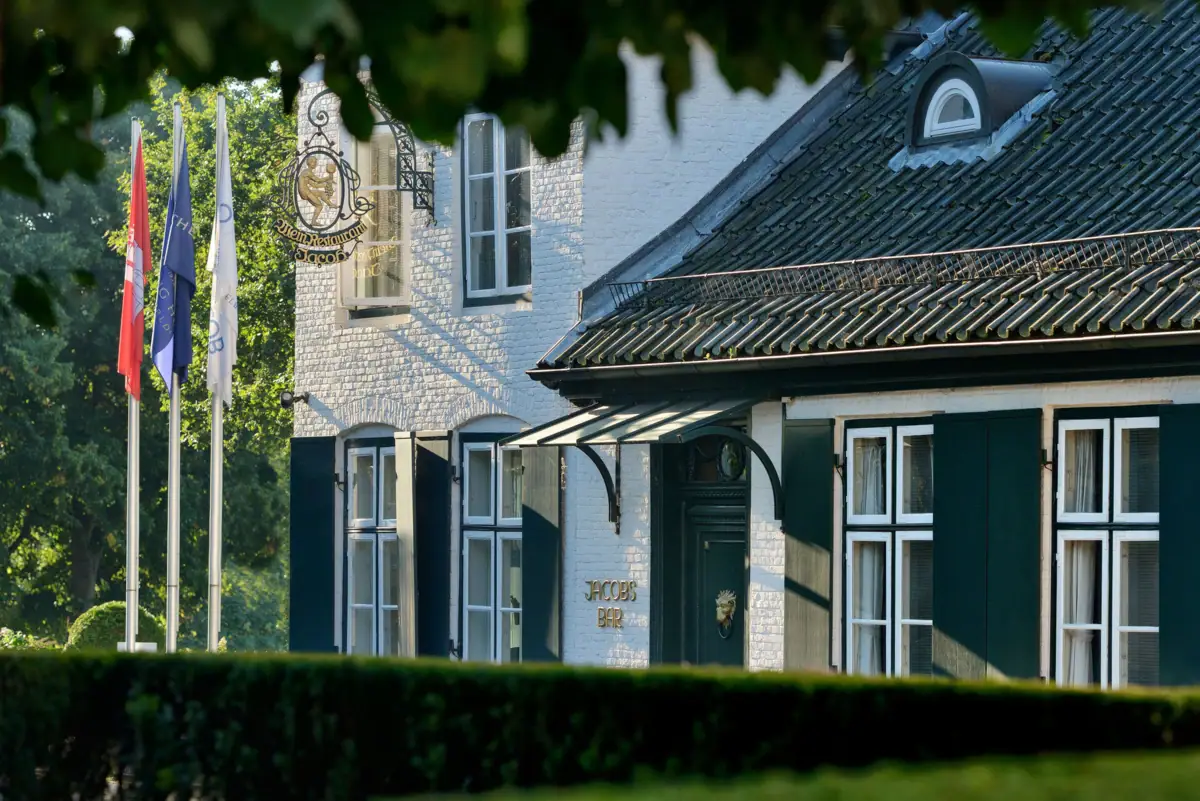 Louis C. Jacob Außenansicht Das Louis C. Jacob Hotel Hamburg mit Fahnen und einer grünen Hecke davor.