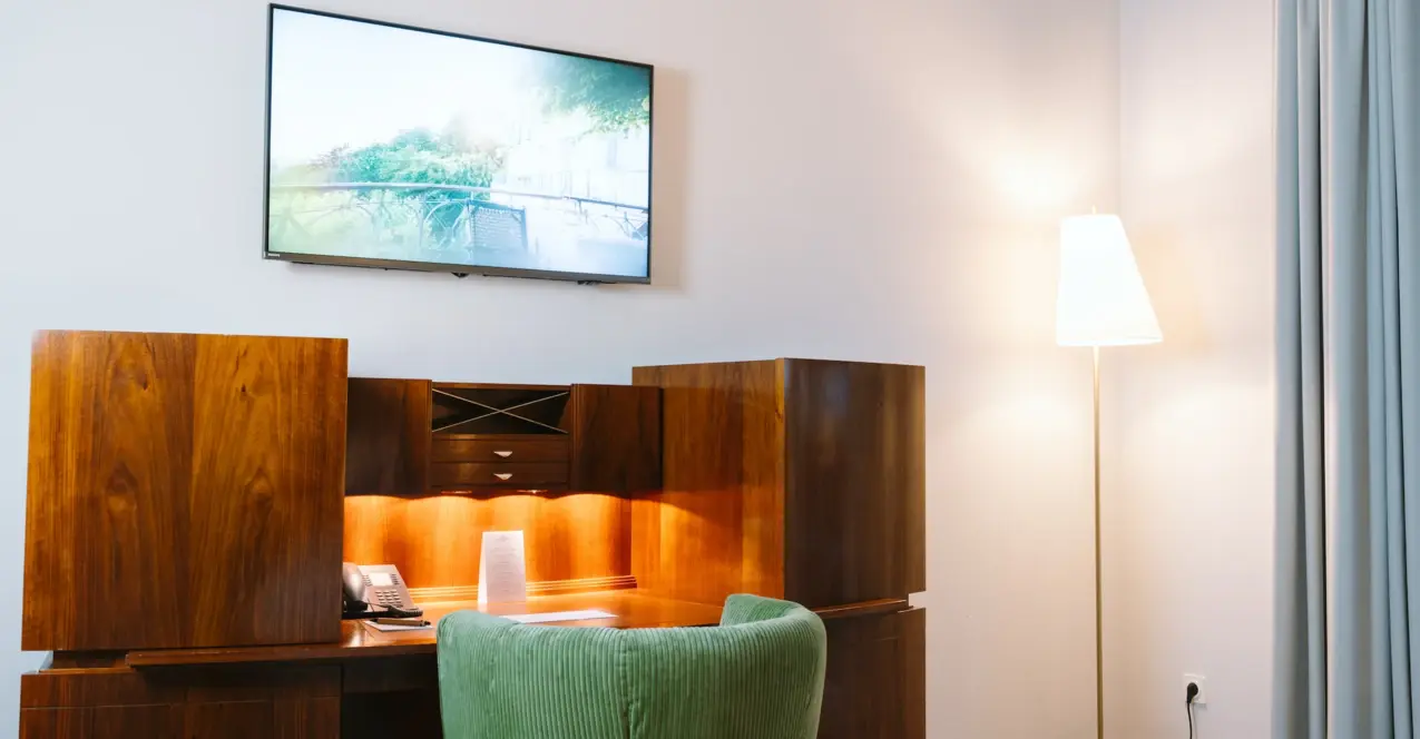 Bureau avec une télévision au mur dans une chambre d'hôtel du Louis C. Jacob Hambourg.