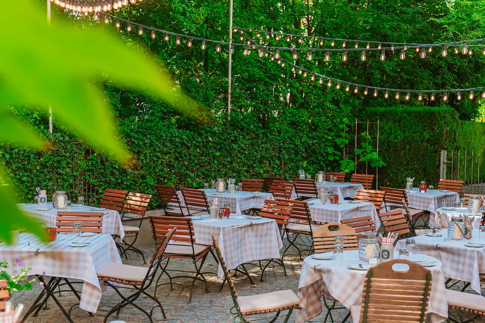 Biergarten der Weinwirtschaft Kleines Jacob mit vielen Tischen und Stühlen sowie Lichterketten.