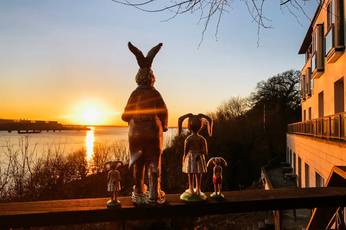 Des figurines de lapins de Pâques sont disposées sur le bastingage de la terrasse Lindent de l'hôtel Louis C. Jacob, avec vue sur le soleil couchant au-dessus de l'Elbe.