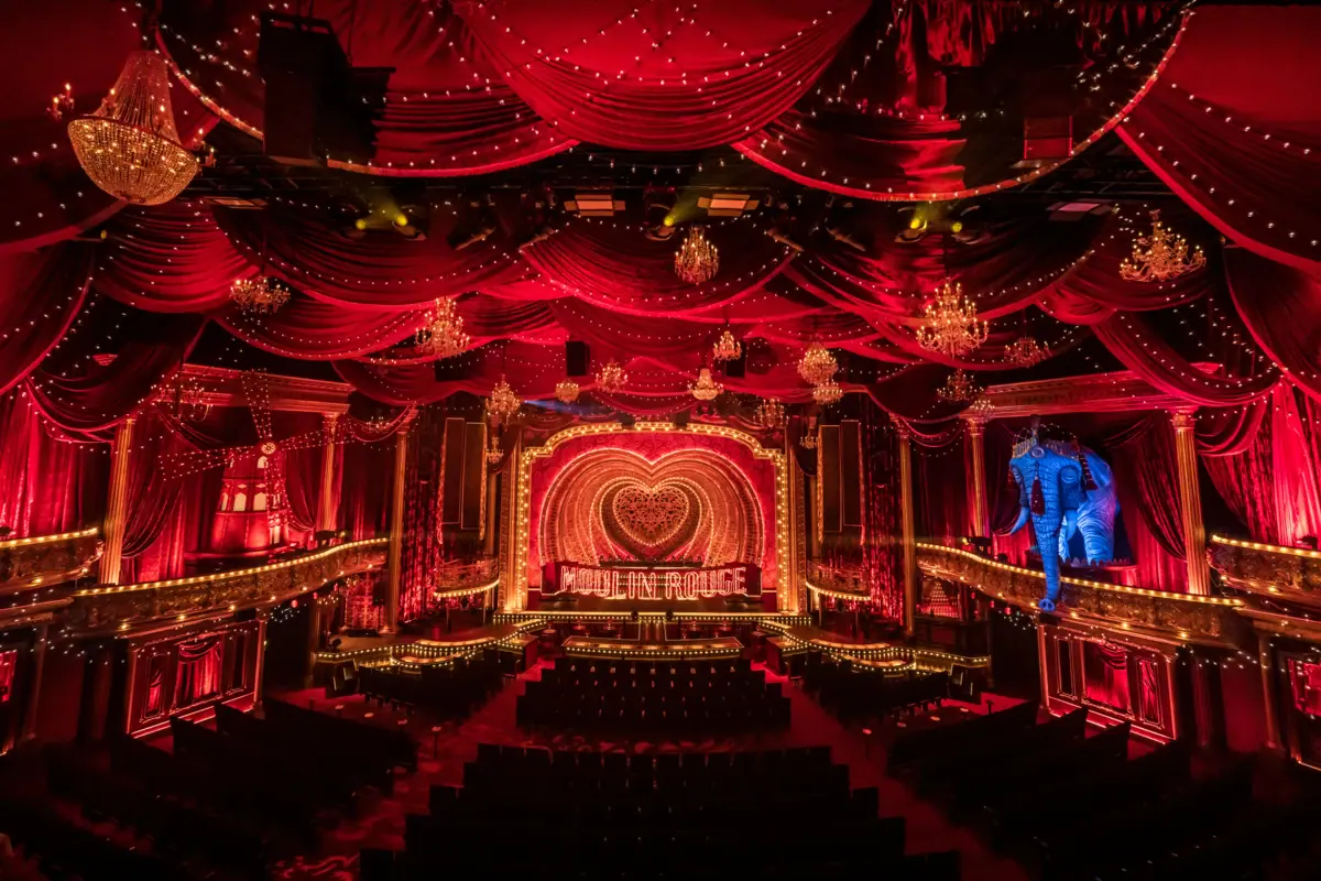 Une scène avec des rideaux rouges et un éclairage de théâtre.