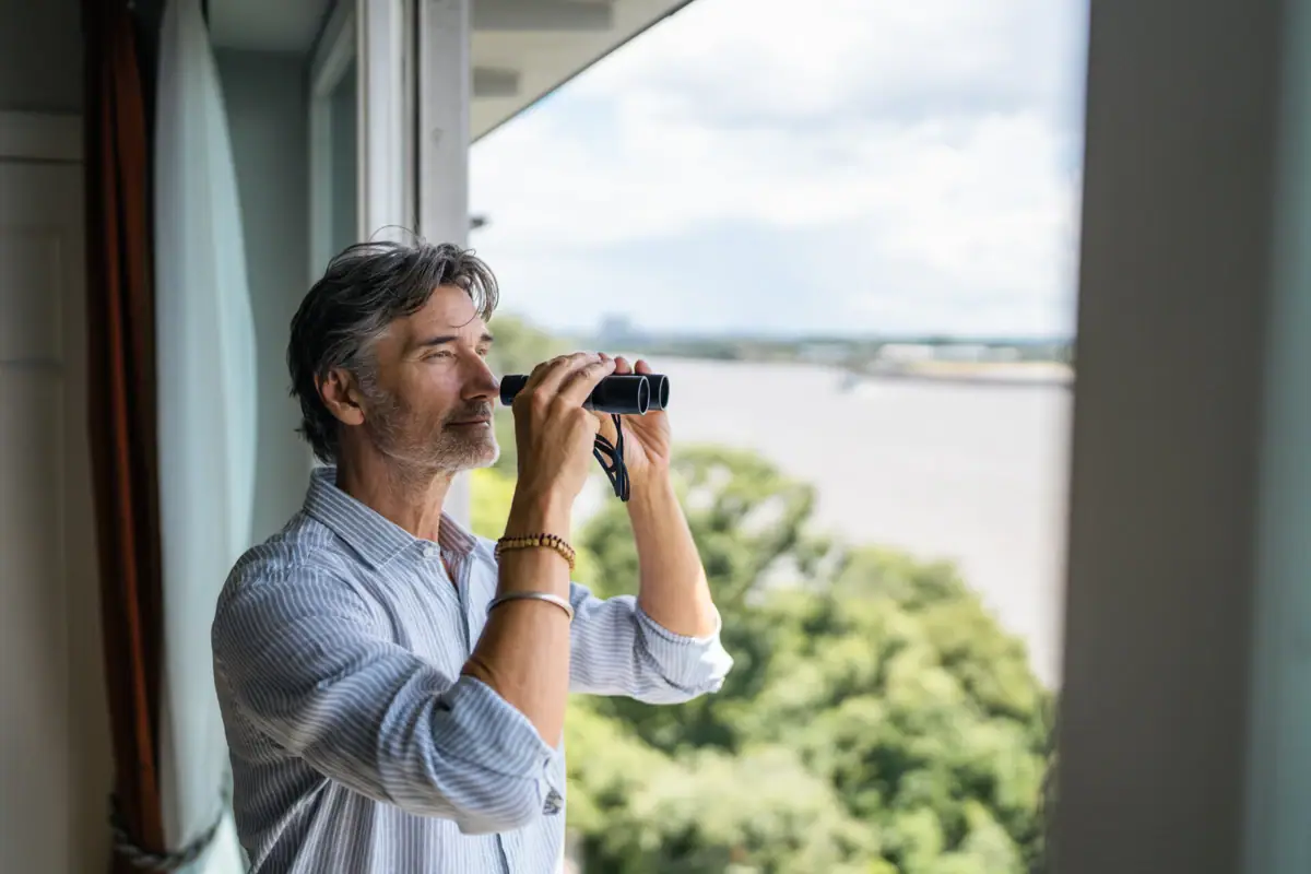 Ausblick Zimmer Louis C. Jacob Ein Mann schaut durch ein Fernglas aus einem Zimmer vom Louis C. Jacob Hotel Hamburg auf die Elbe.