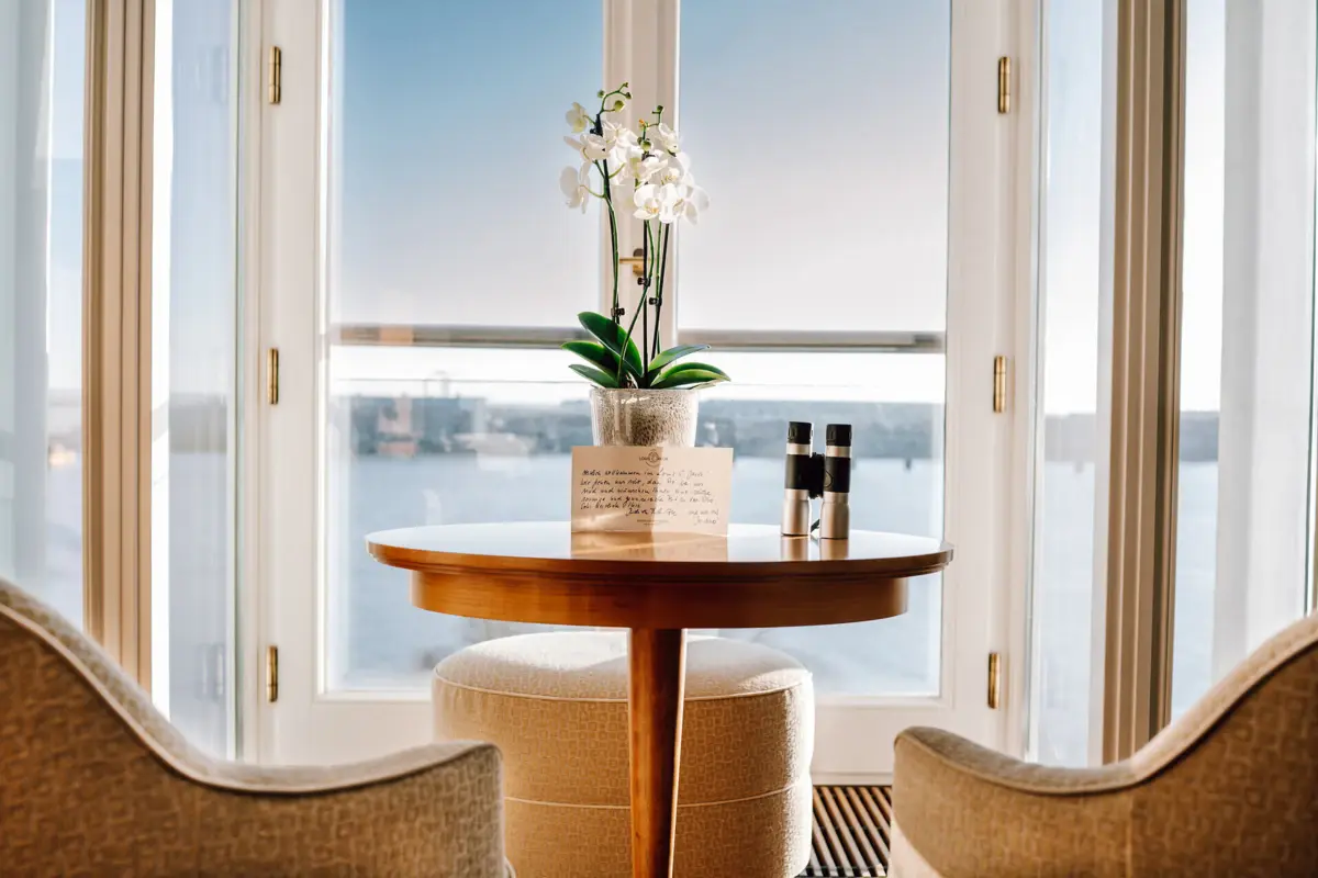 Vor einem Fenster stehen zwei Sessel und ein Tisch mit einer Orchidee darauf.