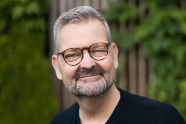 Un homme portant des lunettes et une chemise noire.