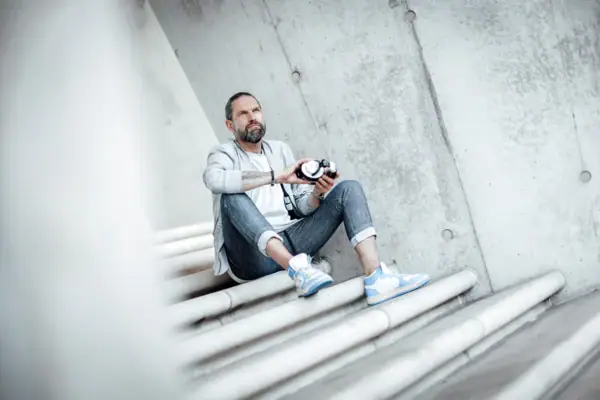 Kai Schwarz Ein Mann sitzt auf Treppen und hält eine Kamera.