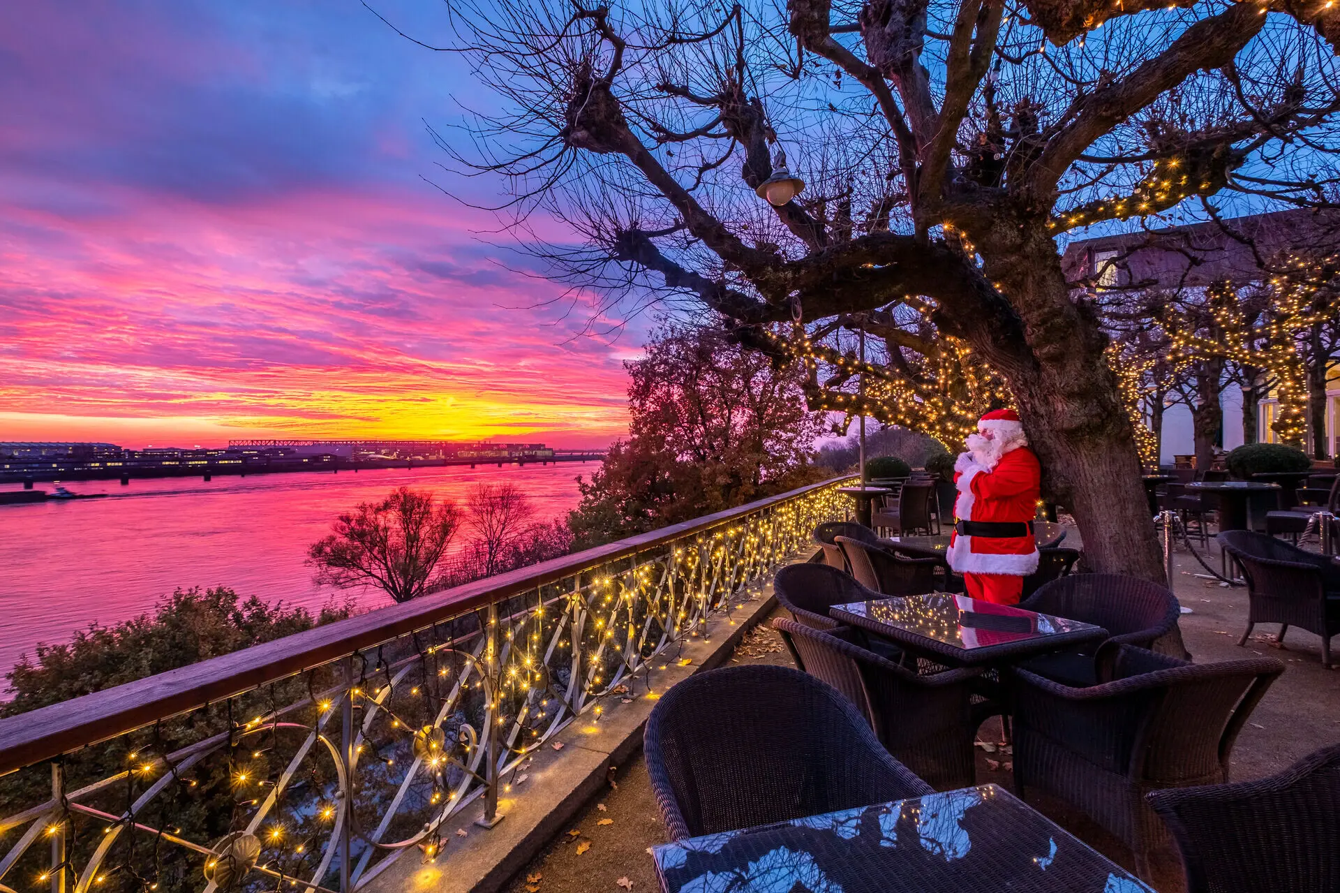 Ein Weihnachtsmann steht auf der Lindenterrasse und das Geländer ist mit Lichterketten geschmückt.