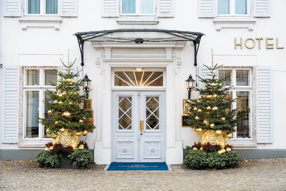 Un bâtiment blanc décoré de sapins de Noël et de guirlandes lumineuses.