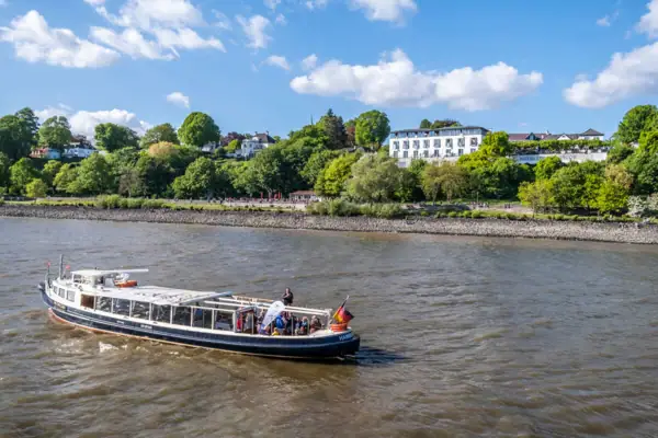 Barkasse MS Jacob auf der Elbe. Im Hintergrund sieht man das Hotel Louis C. Jacob mit der Lindenterrasse.