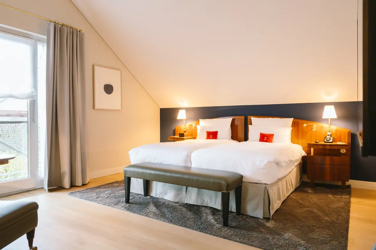 Hotelzimmer im Louis C. Jacob mit einem Bett und einer Bank.