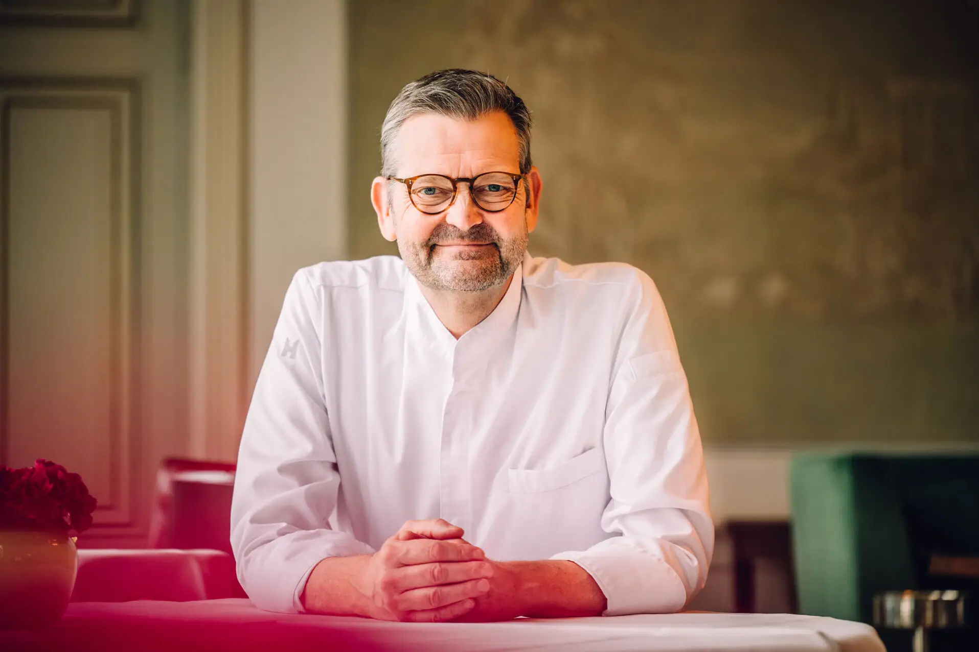 Mann sitzt am Tisch und lächelt offen 