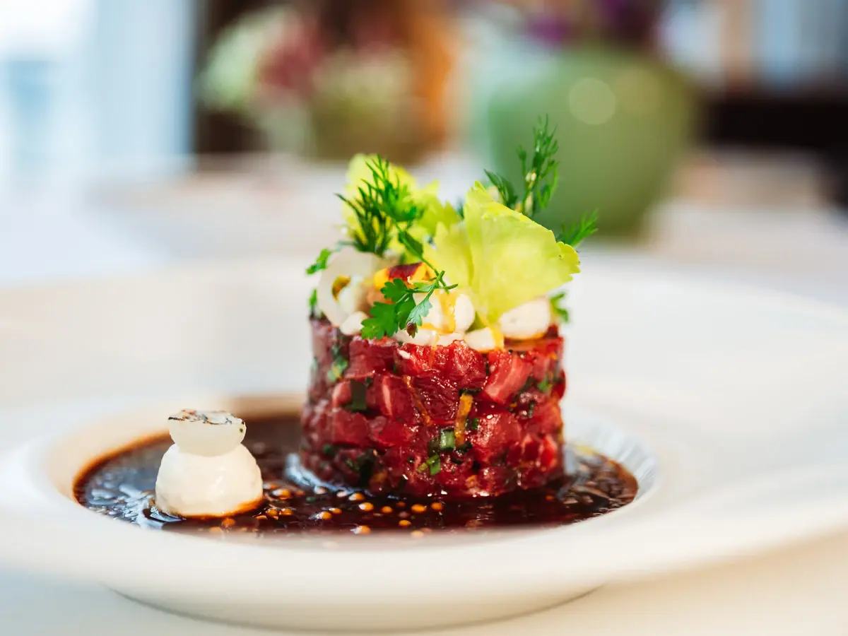 Tatar auf einem Soßenspiegel mit Kräutern dekoriert.