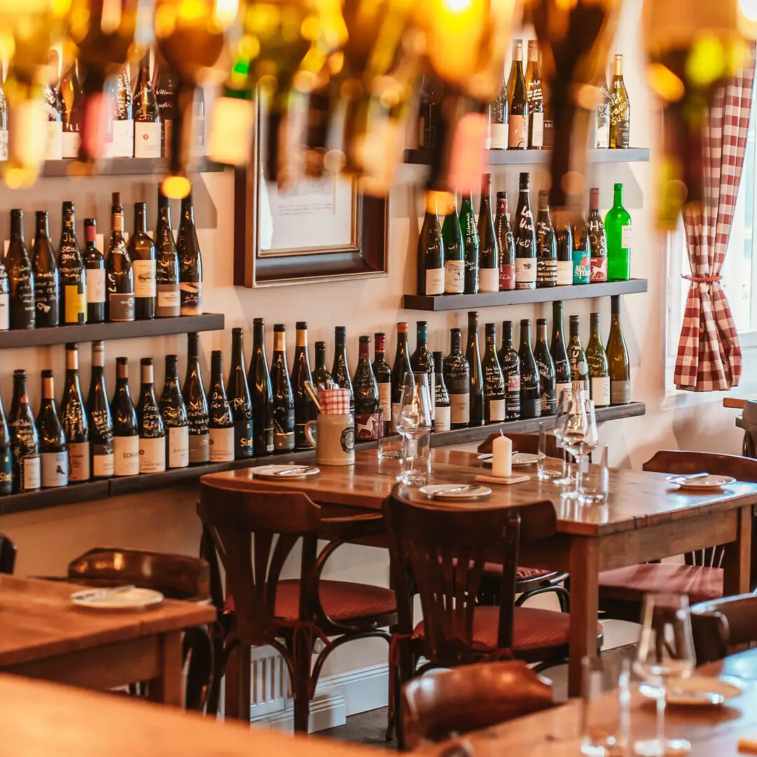Une salle avec des tables, des chaises et des bouteilles de vin.