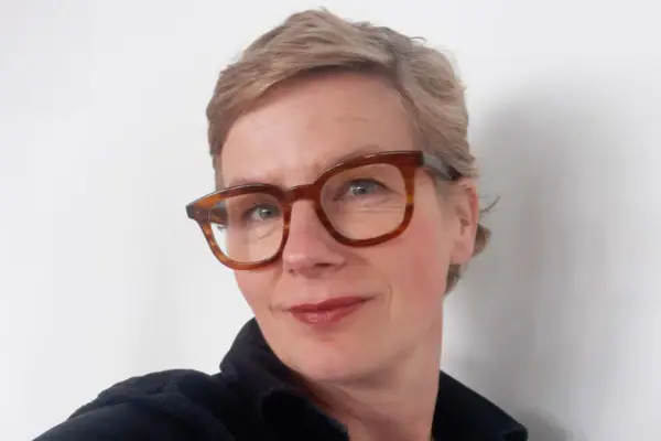 Kirstin Knorr Eine Frau mit kurzen hellen Haaren und einer braunen Brille lächelt..