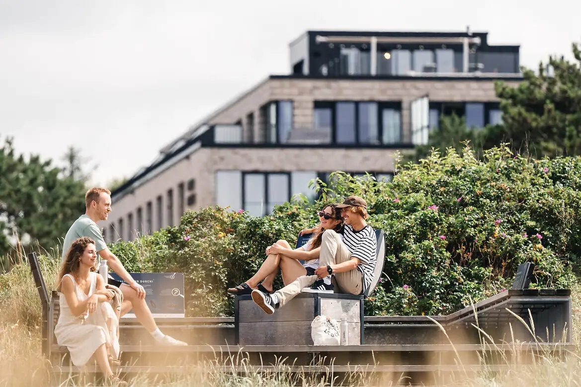 Un groupe de personnes est assis sur un banc à l'extérieur.