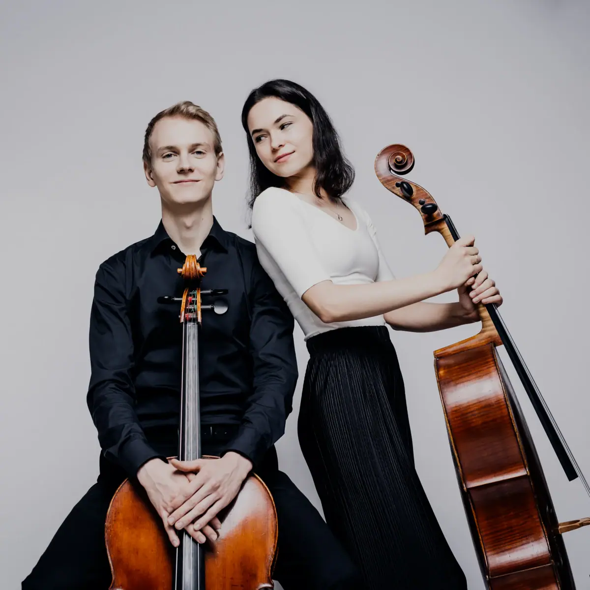 Un homme et une femme posent avec deux violoncelles.