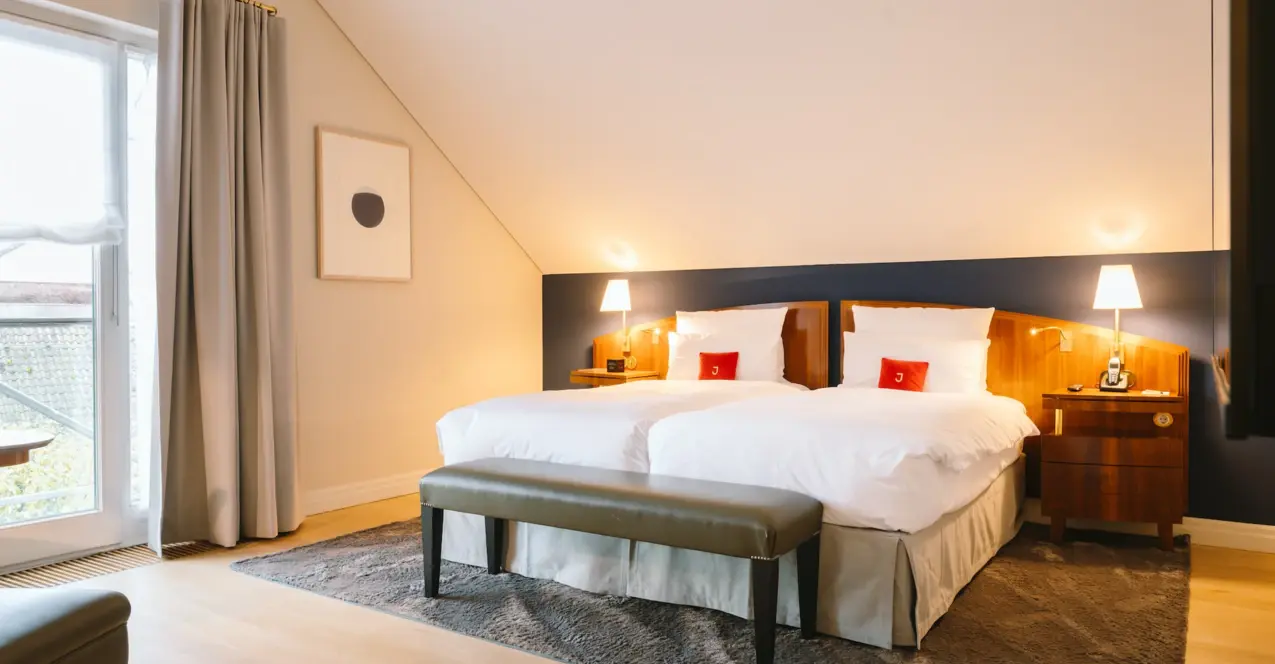 Chambre d'hôtel élégante avec un lit et une banquette à l'hôtel Louis C. Jacob.