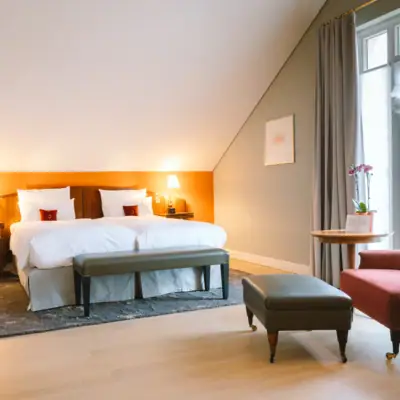 Zimmer mit Bett vor einer orangenen Wand im Hotel Louis C. Jacob.