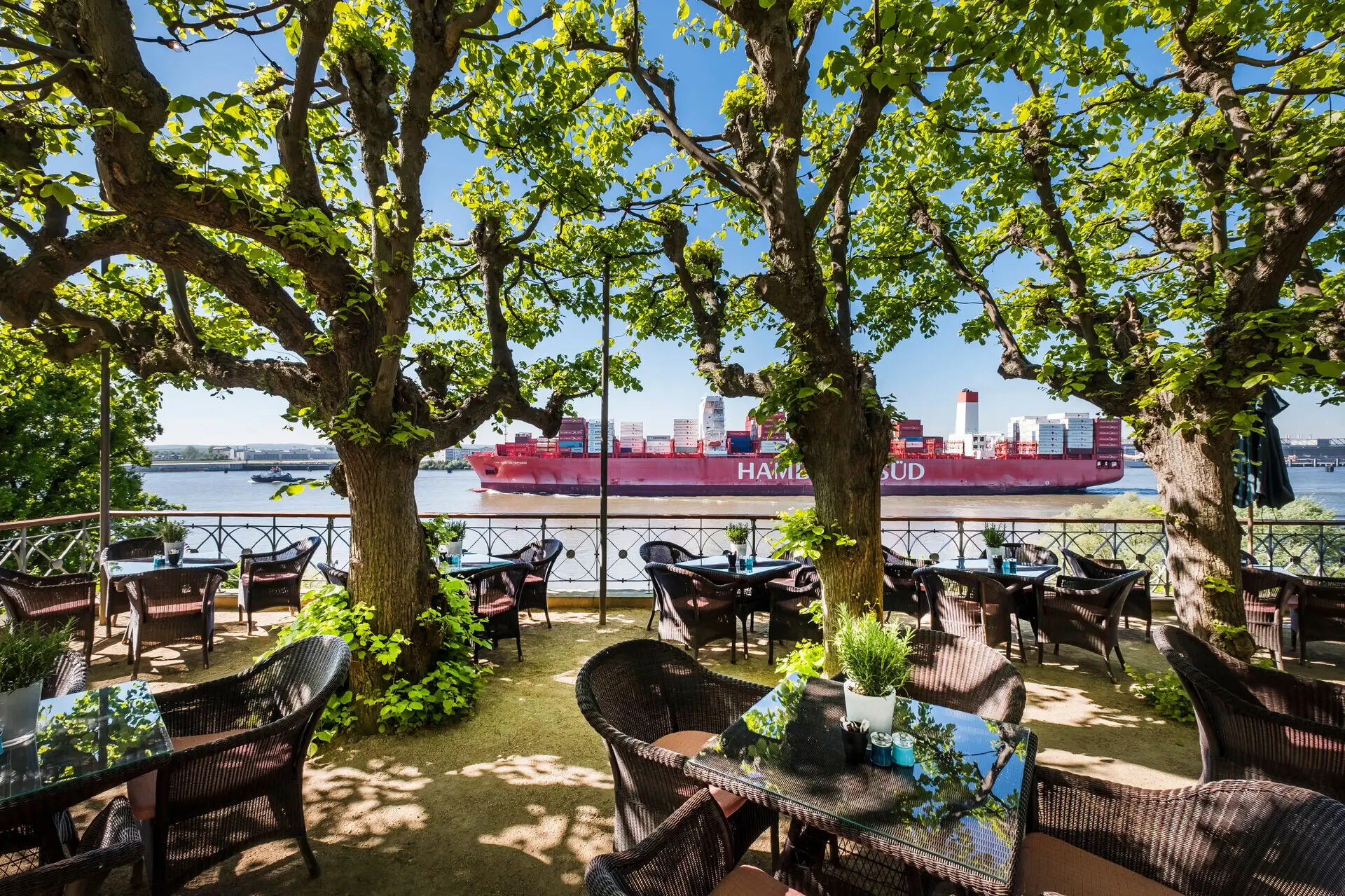 Die Lindenterrasse im Hotel Louis C. Jacob mit Blick auf die Elbe und ein vorbeifahrendes Containerschiff.