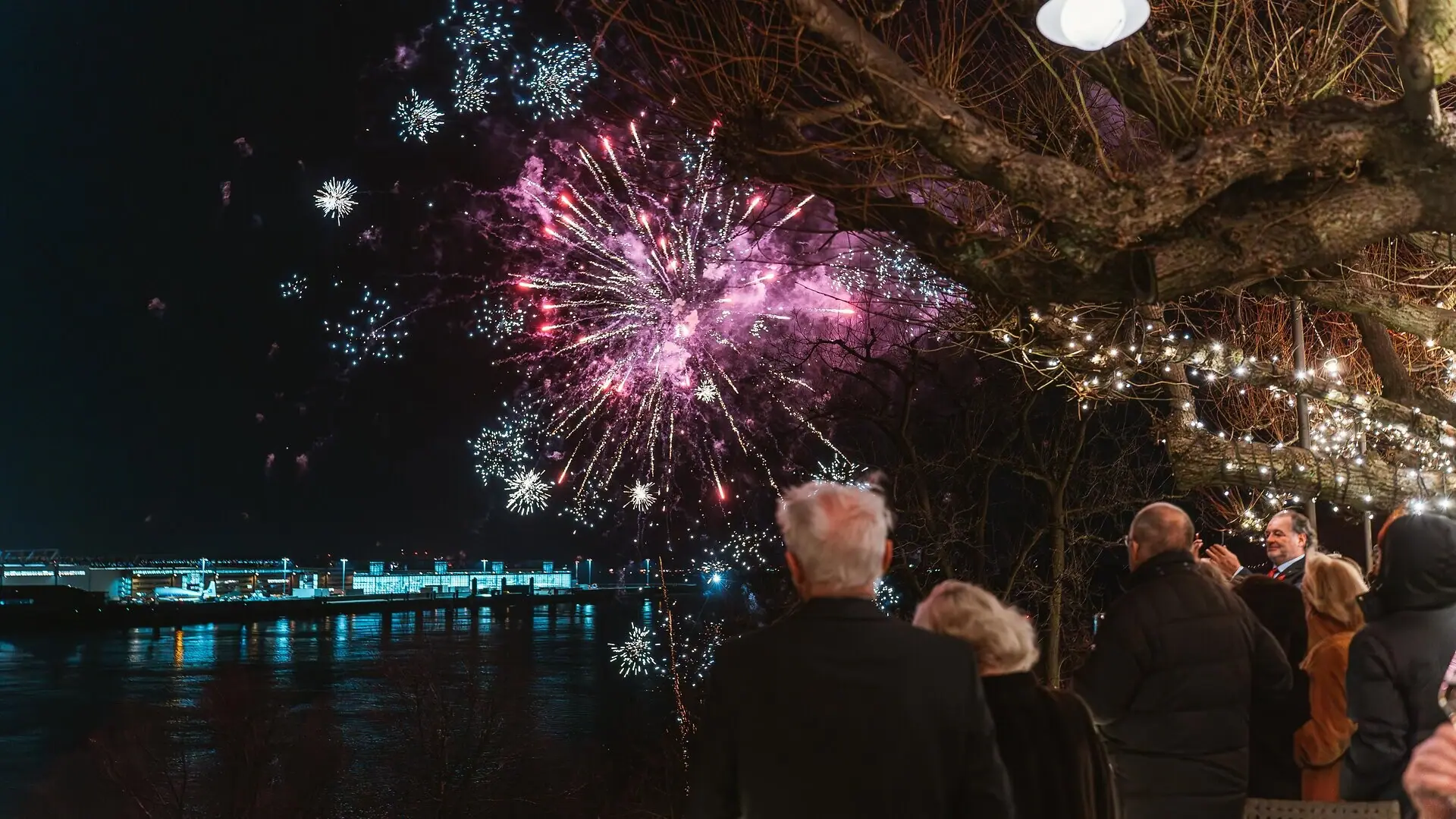 Un groupe de personnes admire le feu d'artifice du réveillon du Nouvel An depuis la terrasse Linden de l'hôtel Louis C. Jacob, à Hambourg.