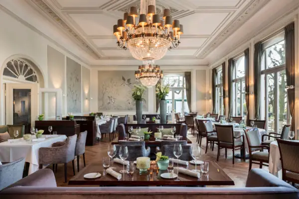 Jacobs Restaurant - Une salle avec des tables, des chaises et des lustres.