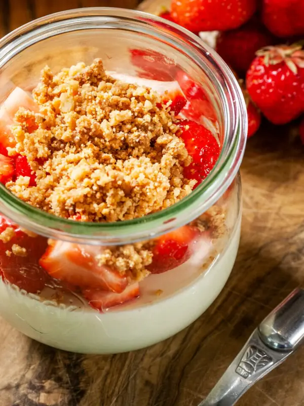Un pot de dessert avec des fraises et une cuillère.